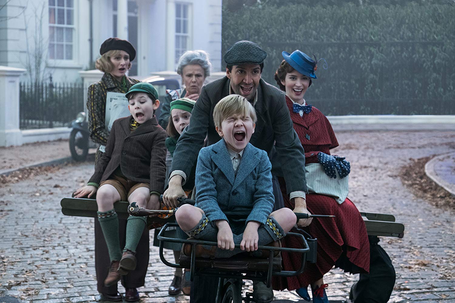 Movie still showing Mary Poppins and Co. riding a bicycle.